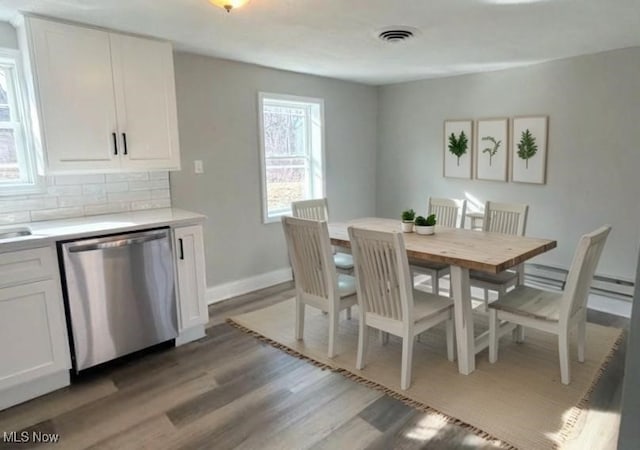 dining area with visible vents, light wood-style flooring, and baseboards