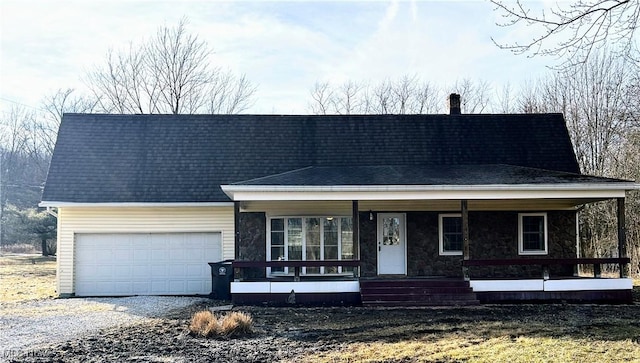 view of front of house featuring gravel driveway, roof with shingles, a porch, a garage, and stone siding