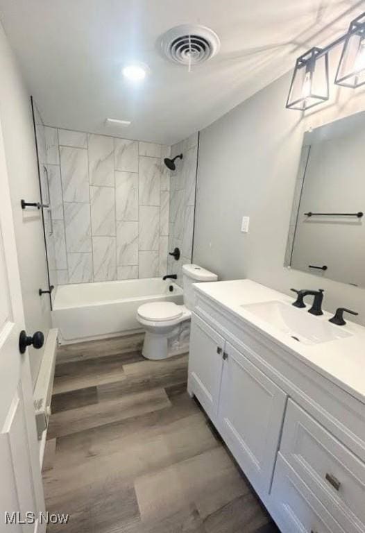 full bath with toilet, wood finished floors, vanity, visible vents, and tub / shower combination