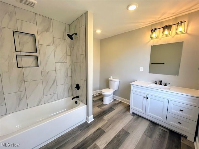 full bathroom with baseboards, visible vents, toilet, wood finished floors, and vanity