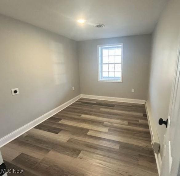 empty room with dark wood-style floors and baseboards