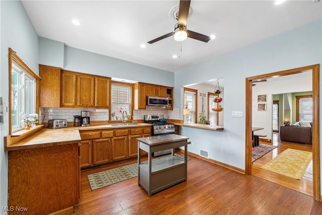 kitchen featuring tasteful backsplash, appliances with stainless steel finishes, brown cabinetry, and a sink