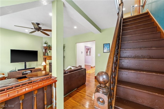 staircase featuring recessed lighting, a fireplace, wood finished floors, a ceiling fan, and beamed ceiling