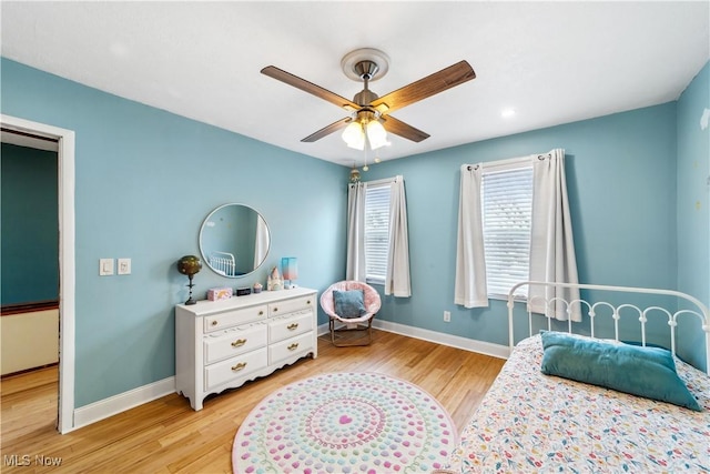 bedroom featuring ceiling fan, light wood-style flooring, and baseboards