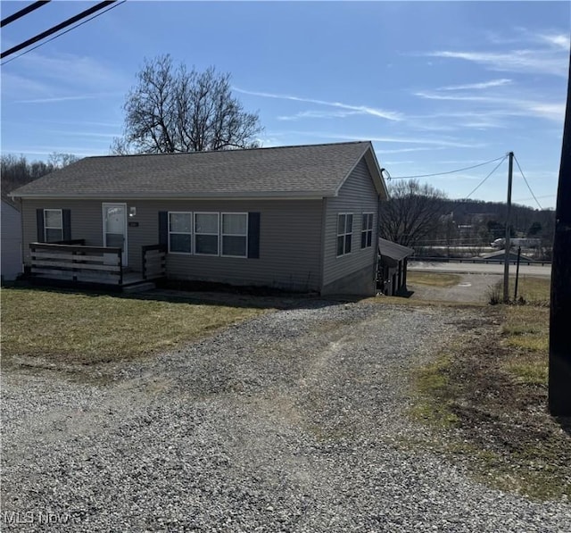 view of front of home with driveway, roof with shingles, and a wooden deck