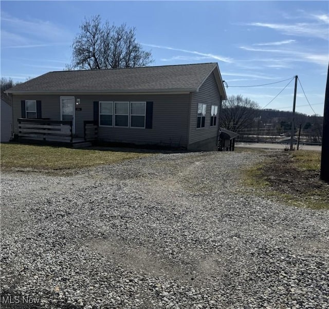 view of front of property featuring driveway and roof with shingles