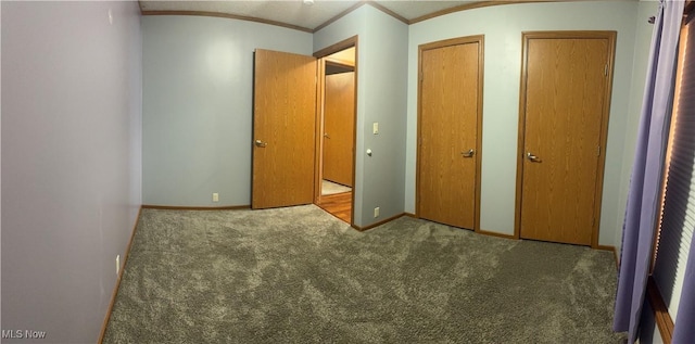 unfurnished bedroom featuring multiple closets, ornamental molding, carpet floors, and baseboards