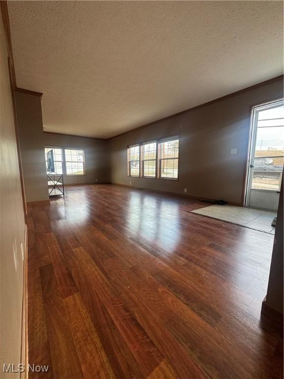 unfurnished living room featuring a textured ceiling, wood finished floors, and baseboards