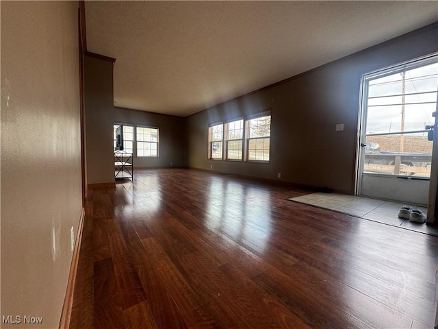 unfurnished living room with wood finished floors and baseboards