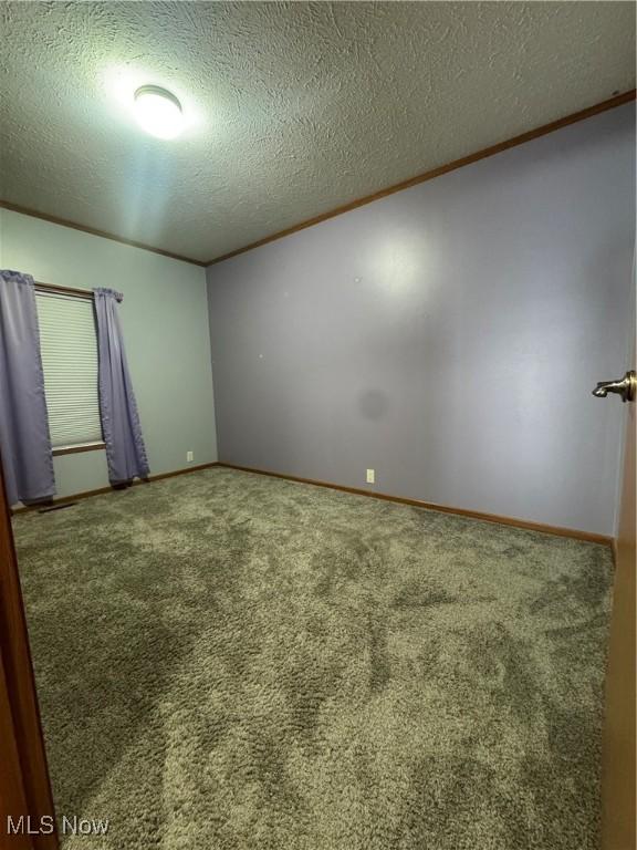 unfurnished room with carpet floors, a textured ceiling, baseboards, and crown molding