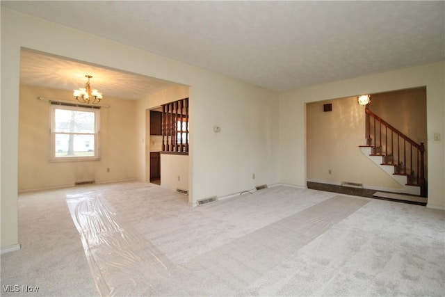 unfurnished living room featuring carpet floors, visible vents, stairway, and an inviting chandelier