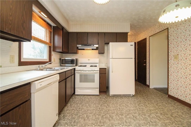 kitchen with light countertops, a sink, white appliances, under cabinet range hood, and wallpapered walls