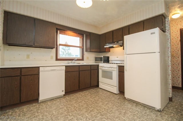 kitchen featuring under cabinet range hood, white appliances, a sink, light countertops, and wallpapered walls