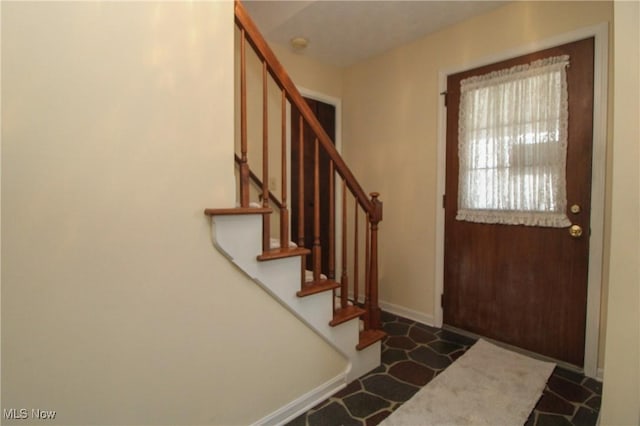 foyer entrance with stairway and baseboards