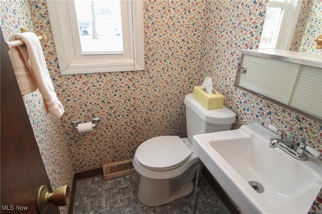 half bath featuring visible vents, a sink, toilet, and a healthy amount of sunlight