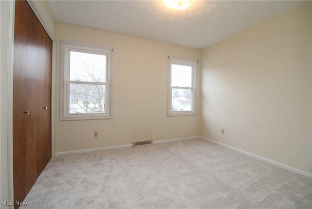 carpeted spare room with visible vents and baseboards