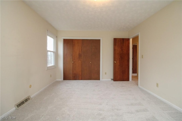 unfurnished bedroom with a closet, visible vents, a textured ceiling, and baseboards