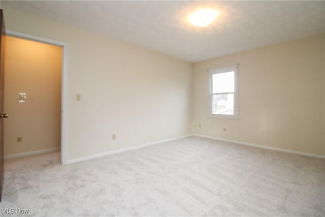 unfurnished room featuring light carpet and baseboards