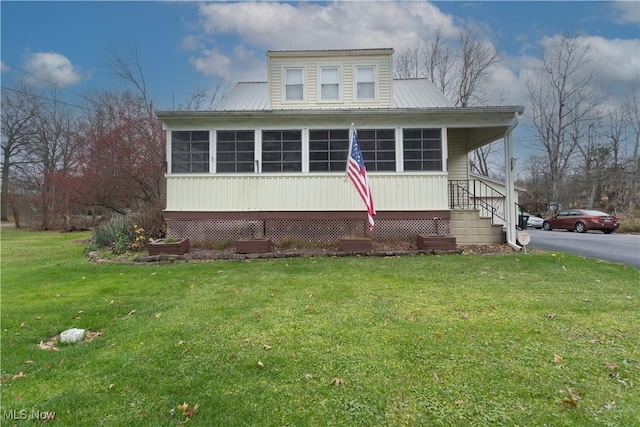 view of front of home featuring a sunroom, metal roof, aphalt driveway, and a front yard