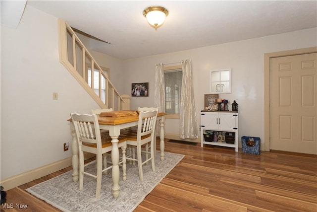 dining area with stairway, baseboards, and wood finished floors