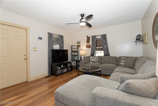 living area featuring a ceiling fan, baseboards, and wood finished floors