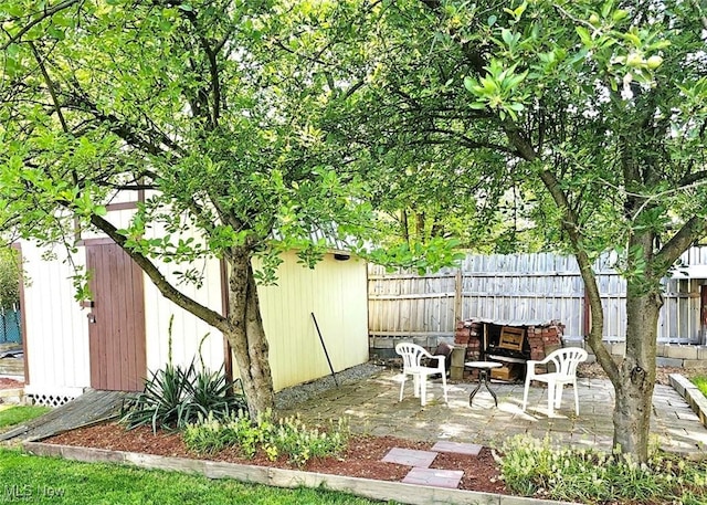 view of patio featuring a storage unit, fence, and an outdoor structure