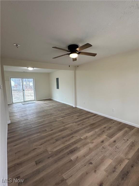 empty room featuring dark wood-style floors, a textured ceiling, baseboards, and a ceiling fan