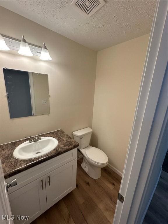 bathroom featuring visible vents, toilet, wood finished floors, a textured ceiling, and vanity