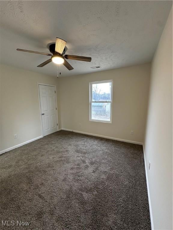 empty room featuring carpet floors, a textured ceiling, and baseboards