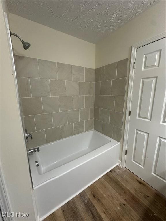 bathroom with a textured ceiling, shower / bath combination, and wood finished floors