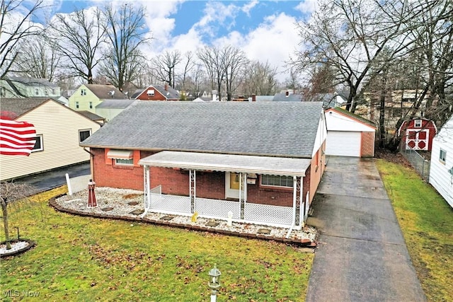 view of front of home featuring brick siding, a shingled roof, an outbuilding, a porch, and a front yard