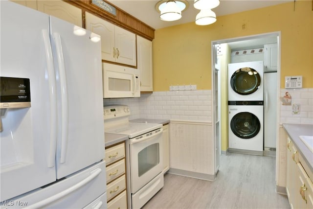 kitchen featuring stacked washer / drying machine, light countertops, decorative backsplash, light wood-type flooring, and white appliances