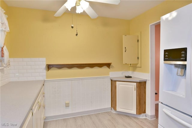 kitchen with light wood-style flooring, white refrigerator with ice dispenser, light countertops, and a ceiling fan