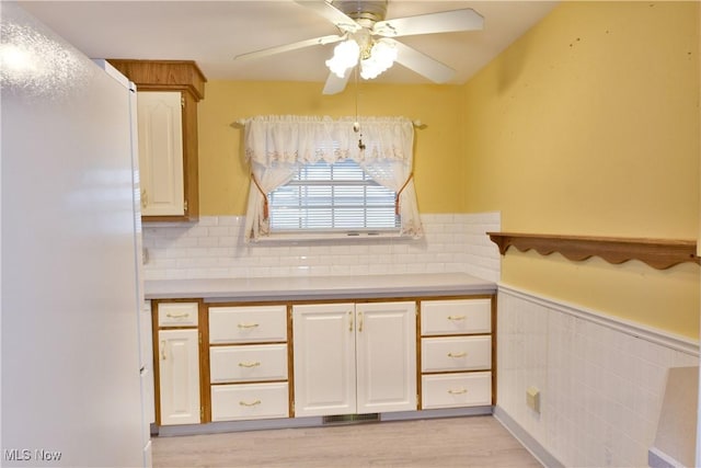 kitchen featuring a ceiling fan, white cabinets, light countertops, wainscoting, and light wood finished floors