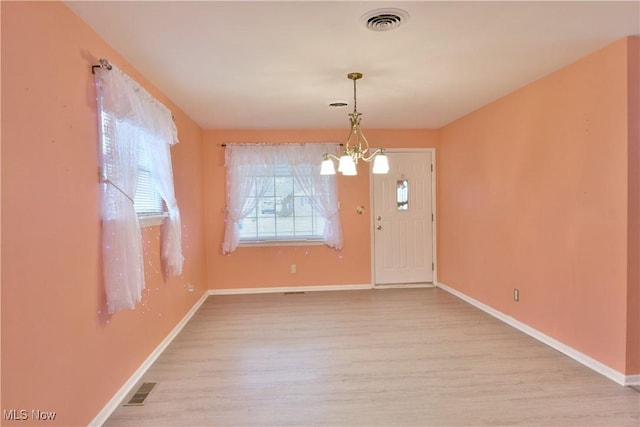 interior space with baseboards, visible vents, a chandelier, and wood finished floors