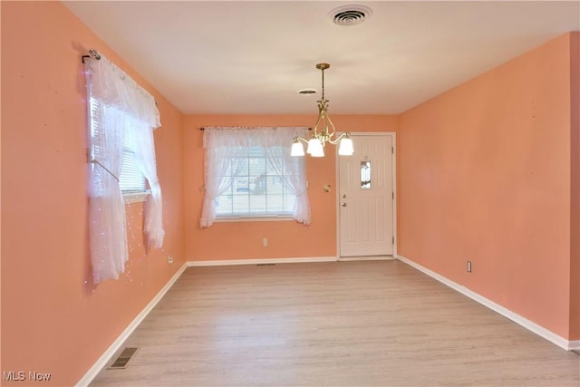 foyer with baseboards, visible vents, a notable chandelier, and wood finished floors