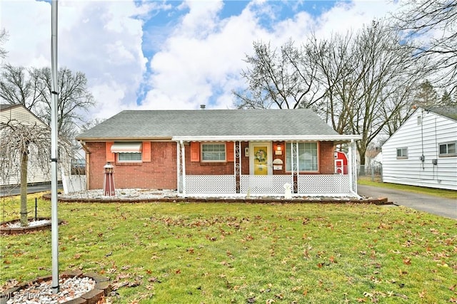 ranch-style house with a porch, brick siding, driveway, and a front lawn