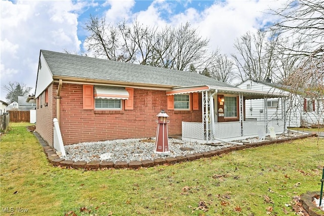 view of front of property with a front yard, brick siding, fence, and roof with shingles