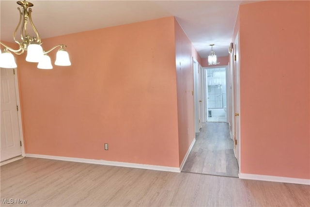 corridor with a notable chandelier, baseboards, and wood finished floors