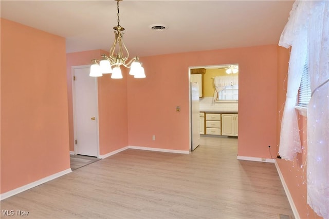 unfurnished room with light wood-type flooring, baseboards, visible vents, and a chandelier