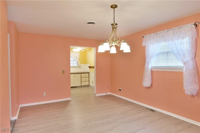 unfurnished dining area with baseboards, light wood-type flooring, visible vents, and a notable chandelier