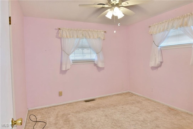 carpeted empty room featuring a ceiling fan, visible vents, and baseboards