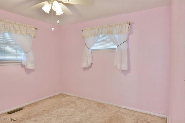 carpeted empty room featuring visible vents, ceiling fan, and baseboards