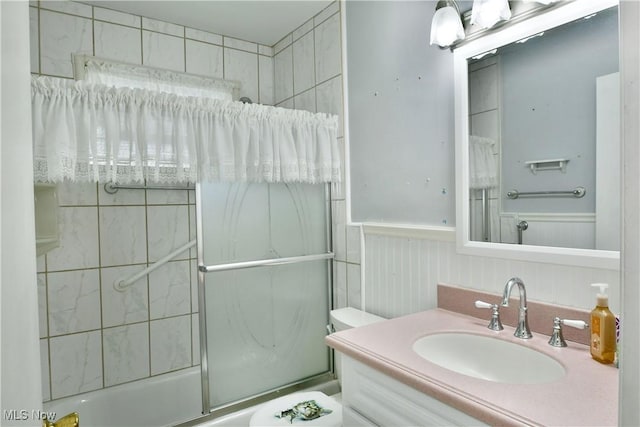 bathroom featuring enclosed tub / shower combo, wainscoting, and vanity