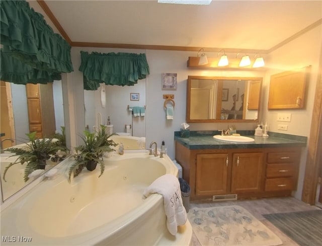 bathroom with ornamental molding, visible vents, vanity, and a tub with jets