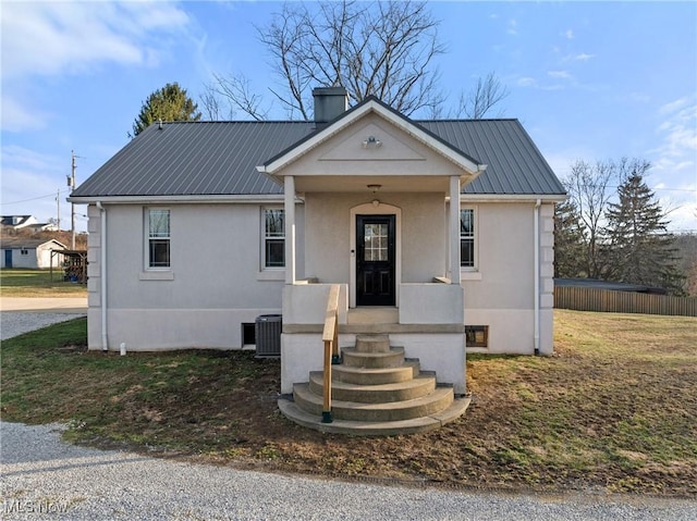 view of front of home with a chimney, central AC unit, metal roof, and stucco siding