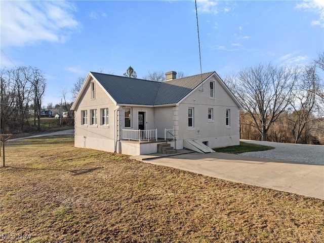 back of house featuring metal roof and a chimney