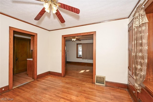 unfurnished room with ornamental molding, visible vents, light wood-style flooring, and baseboards