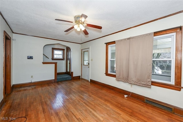 spare room with baseboards, visible vents, ornamental molding, hardwood / wood-style floors, and a textured ceiling