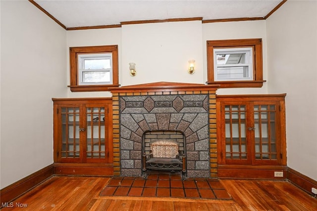 unfurnished living room with ornamental molding, a fireplace, wood finished floors, and baseboards